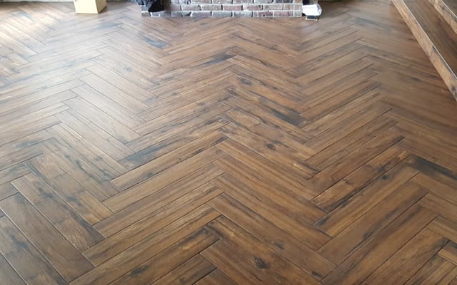 Wood-look floor laid in a herringbone pattern with a plank border