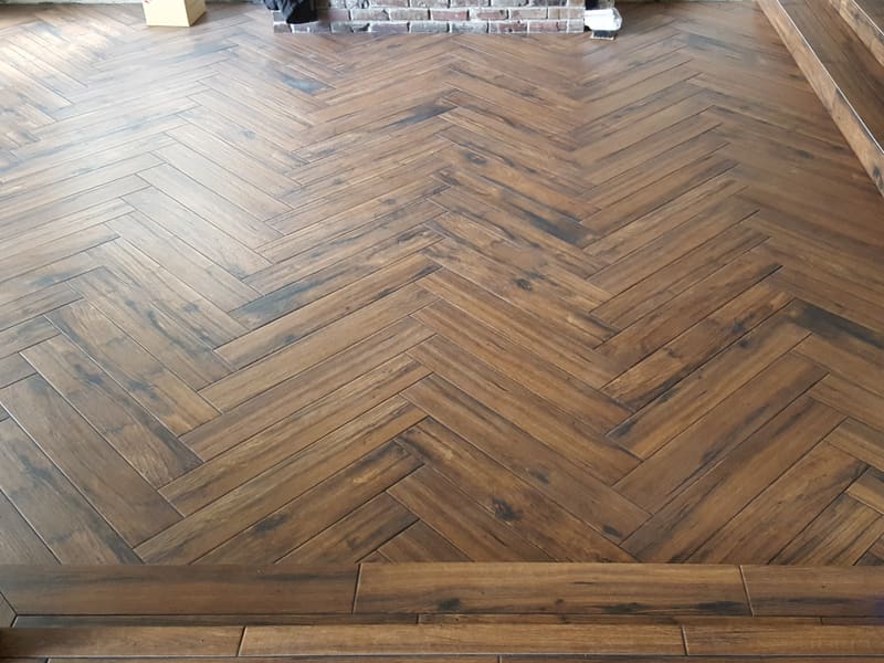 Wood-look floor laid in a herringbone pattern with a plank border